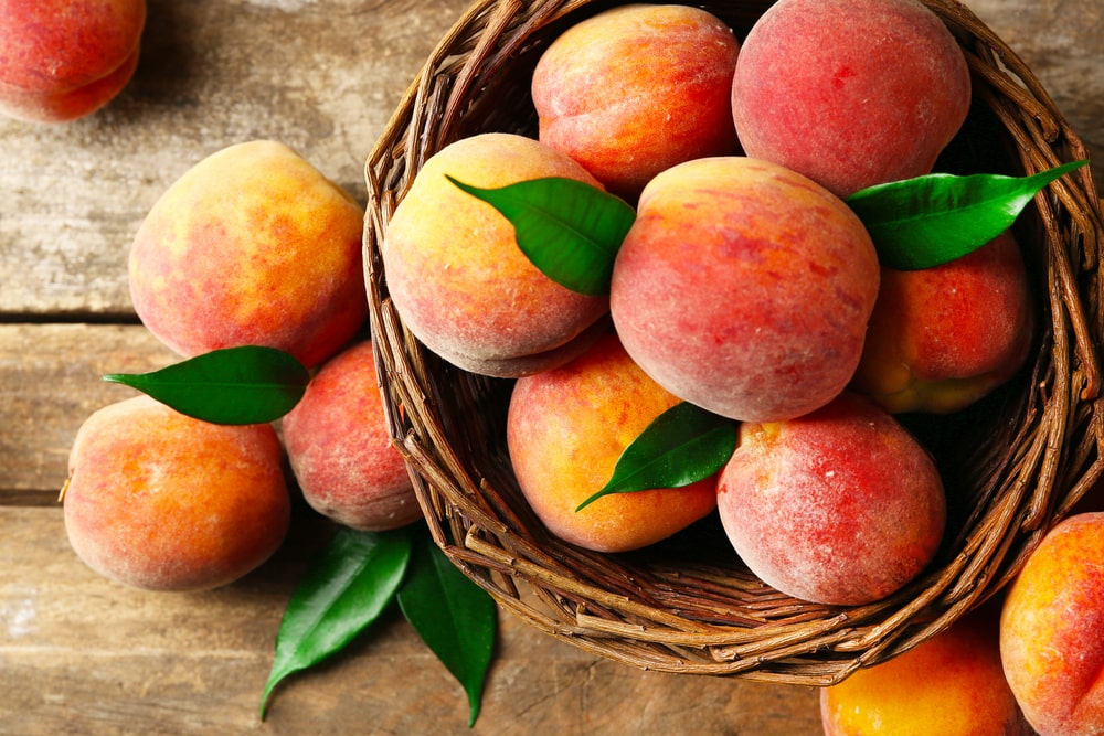 Peaches in a basket with a wooden background