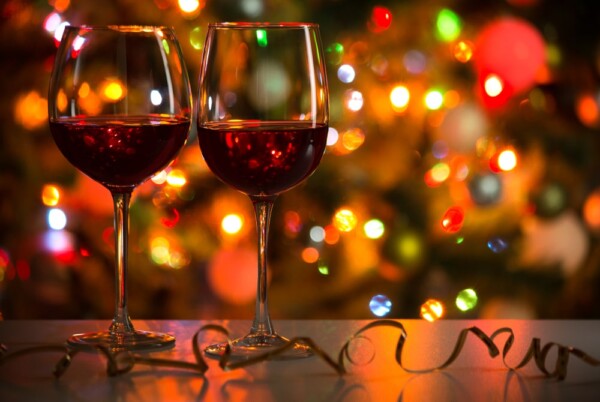 Two wine glasses behind a lit Christmas tree