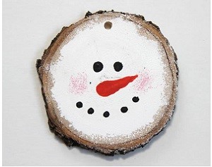 A snowman face painted on a tree trunk